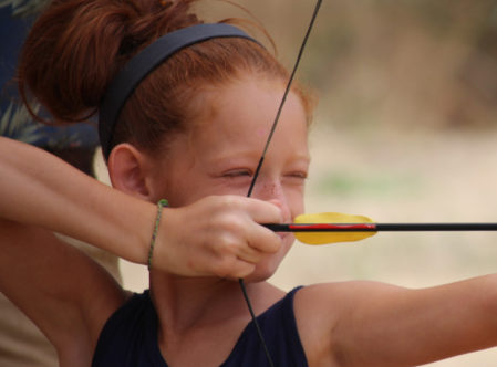 girl pulling aiming her bow getting ready to shoot a target