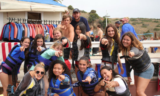 counselors and campers posing for a photo with lifejackets on by the dock