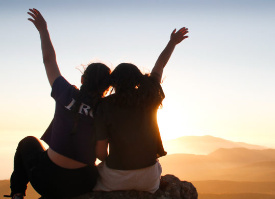 campers with their hands in the air at sunset