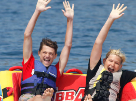 campers seated on a tube being pulled by a boat