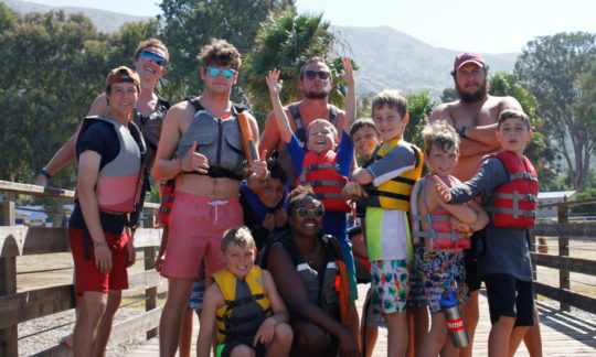 staff and campers posing on the dock while wearing life jackets